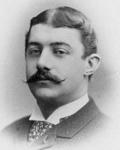 Man in suit with mustache poses for picture. 