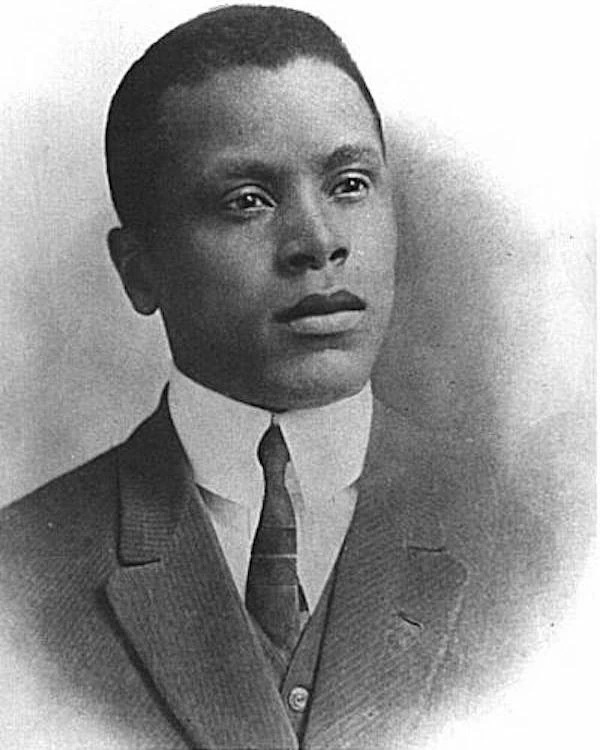 Black and white image of young adult wearing a 3 piece suit and tie.