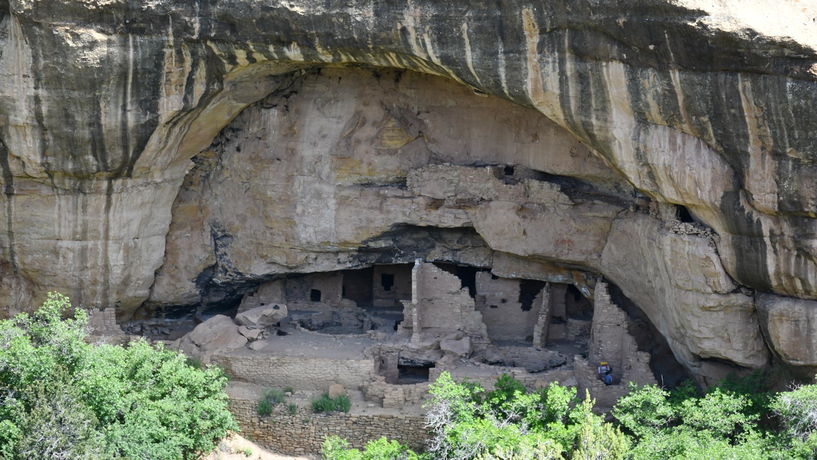 A view of Oak Tree House, a stone-built village constructed under a sandstone overhang.