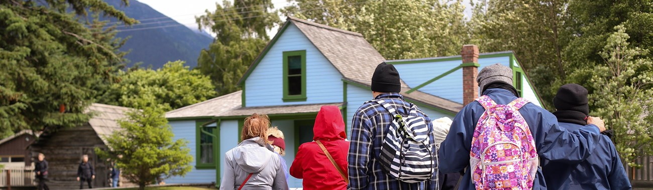 People gathered in front of a house with fence sign 