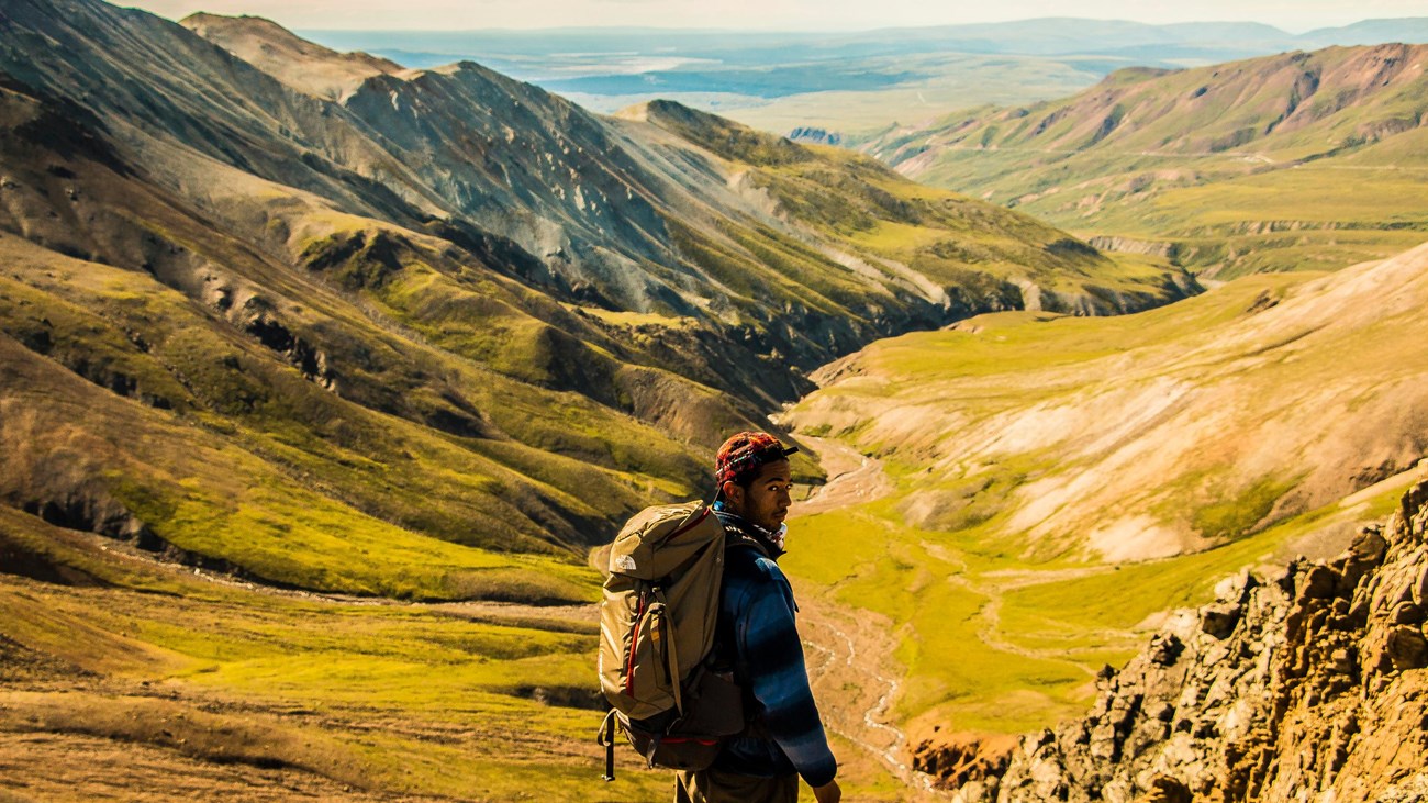 a man standing on a ridge top with a large backpack on