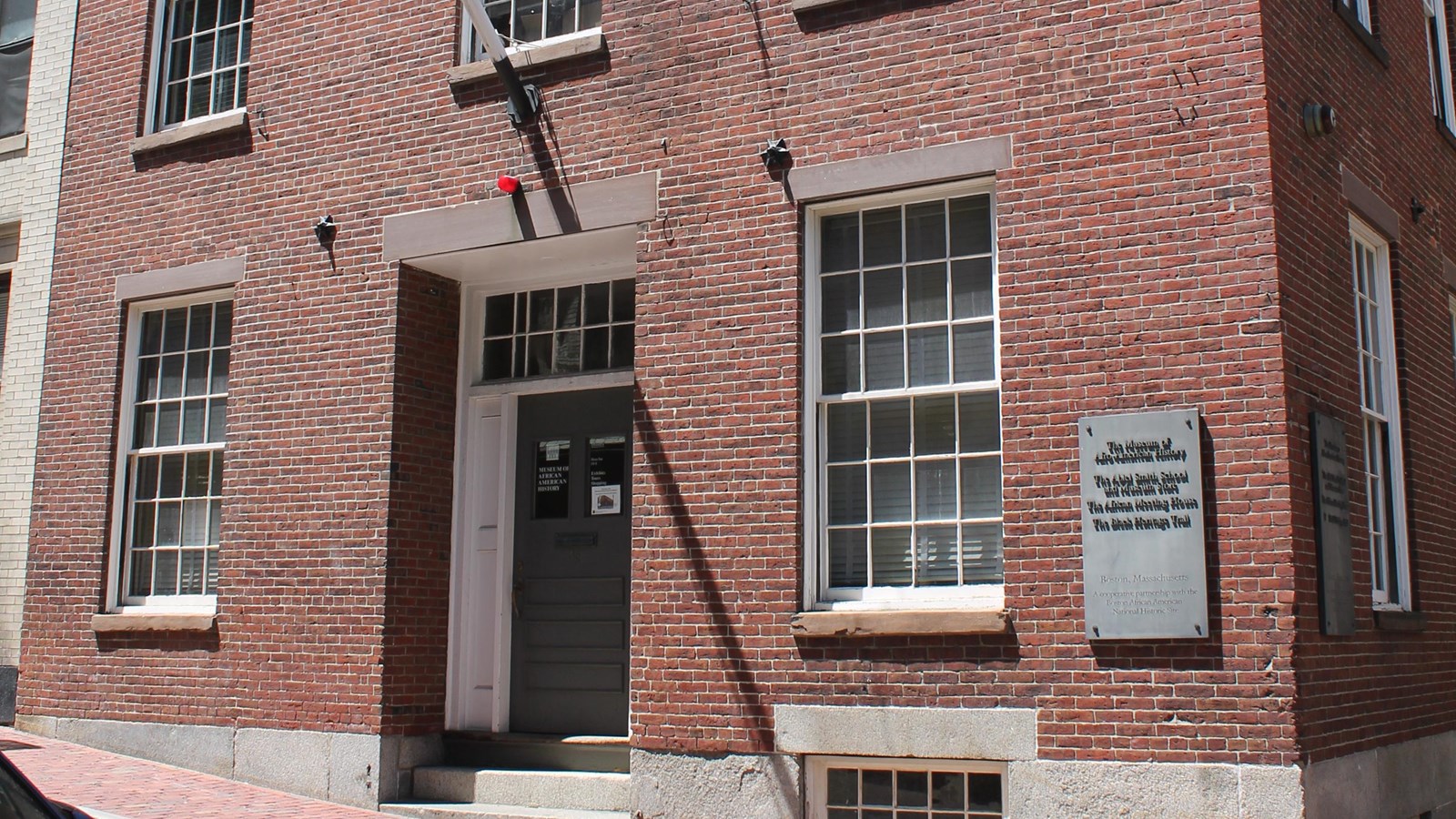 A two-story brick building with the entrance in the center and two windows on either side.