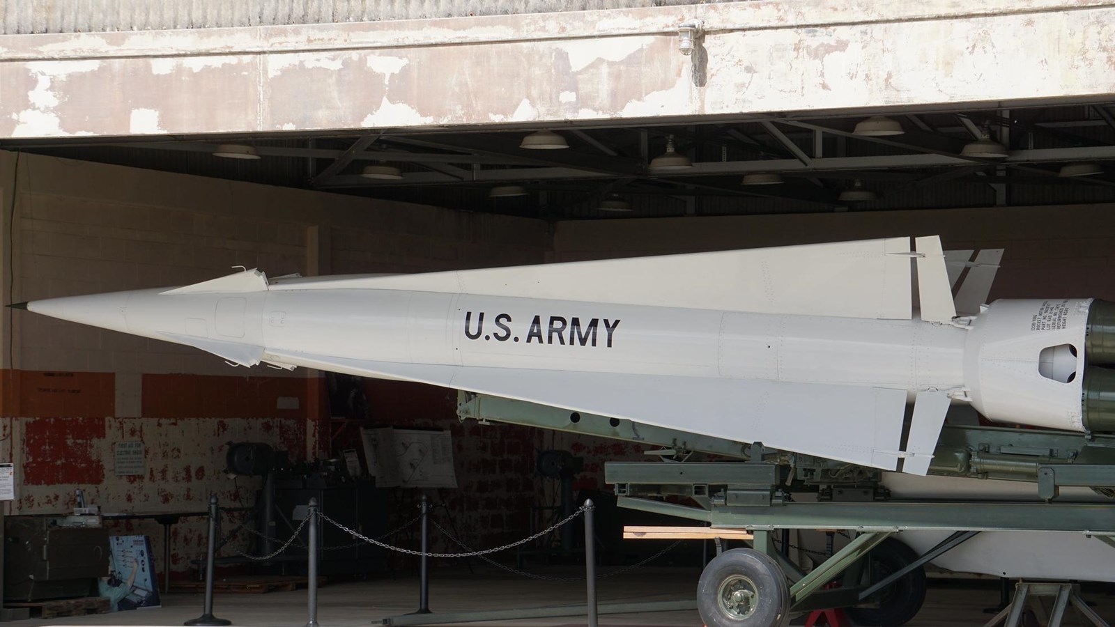 A large green missile with a white tip is sitting on a carriage.  Writing reads 