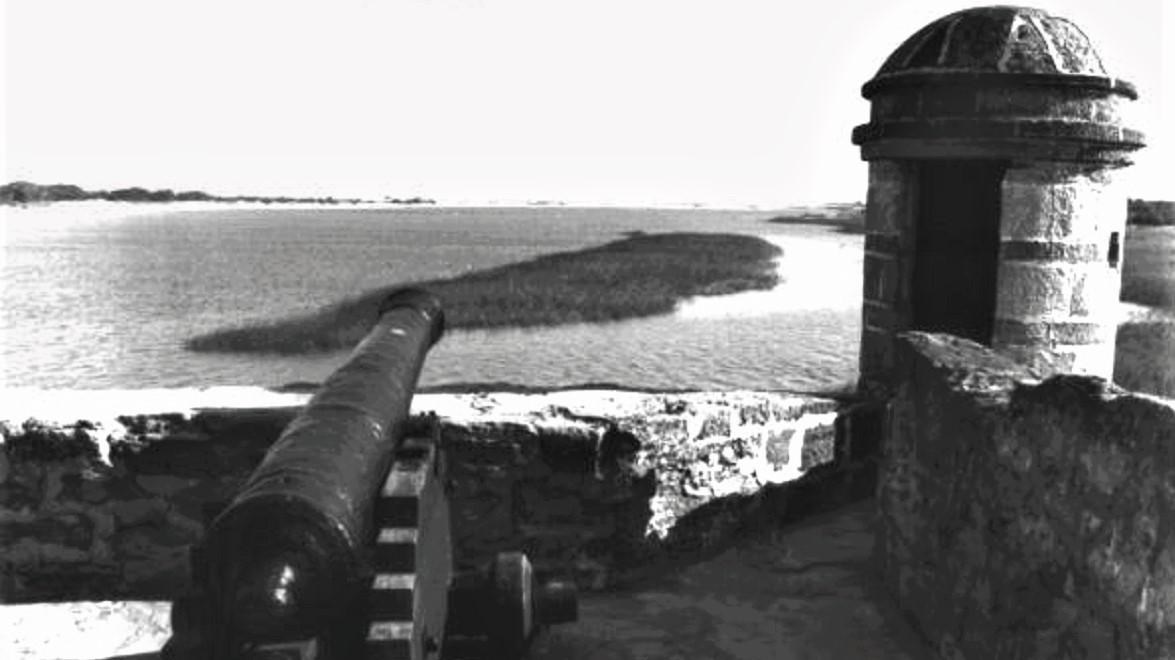 Black and white photo cannon and sentry tower. Bayfront and marshland