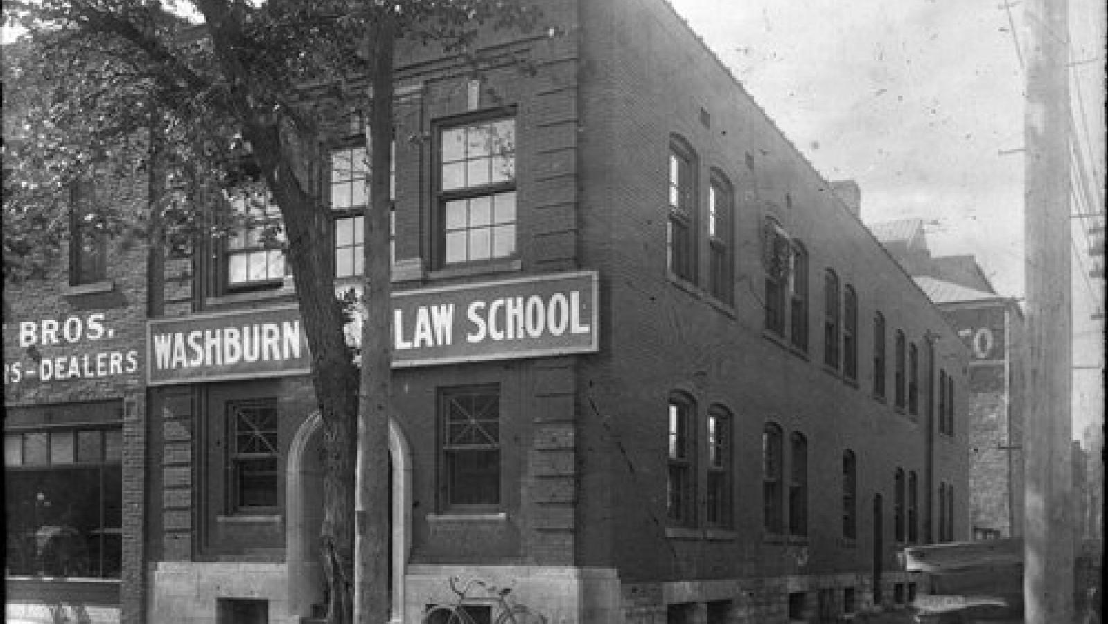 A black and white picture of the front of an old, 20th century, brick law school.