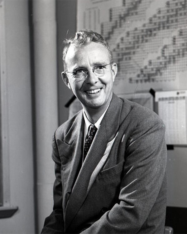Black and white photo of a man in a suit smiling at the camera.