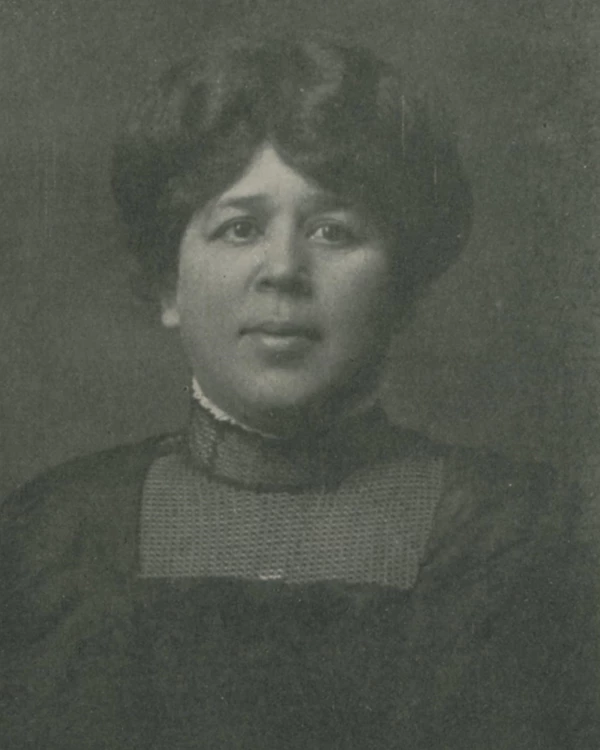 Black and white photograph of woman in high-necked black dress and close-styled hair.