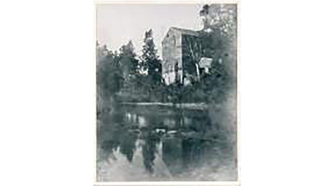 A historic image of a mill along a river.