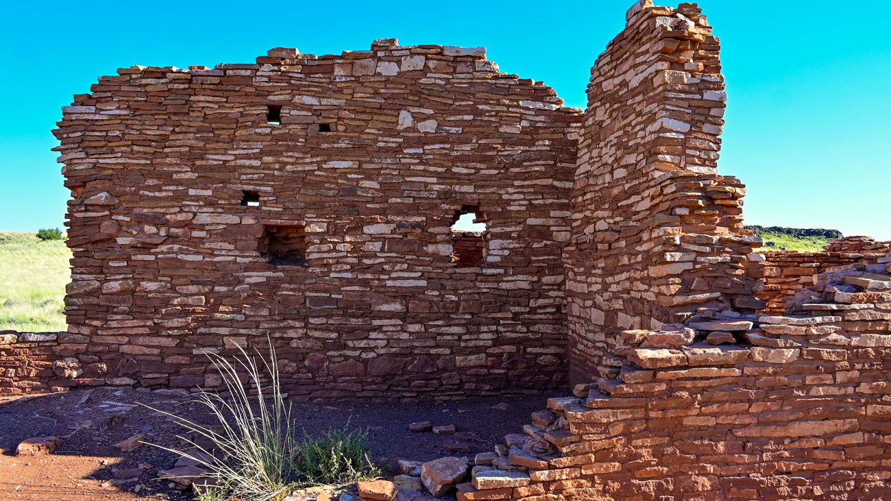 A red and tan sandstone pueblo is set against a deep blue sky