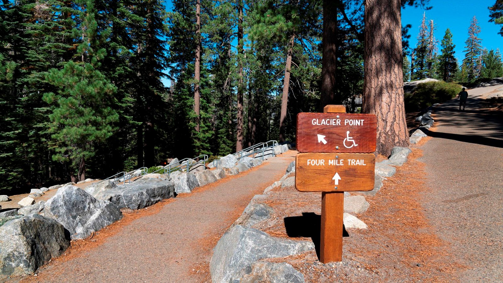 Wooden trail sign at a fork of two trails.