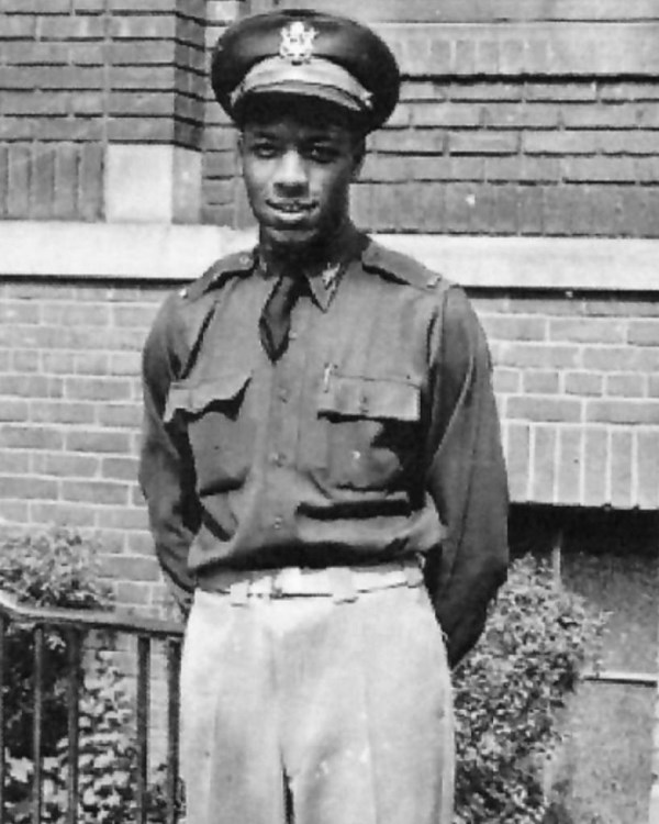 African American male in military uniform facing the viewer in front of a brick building.