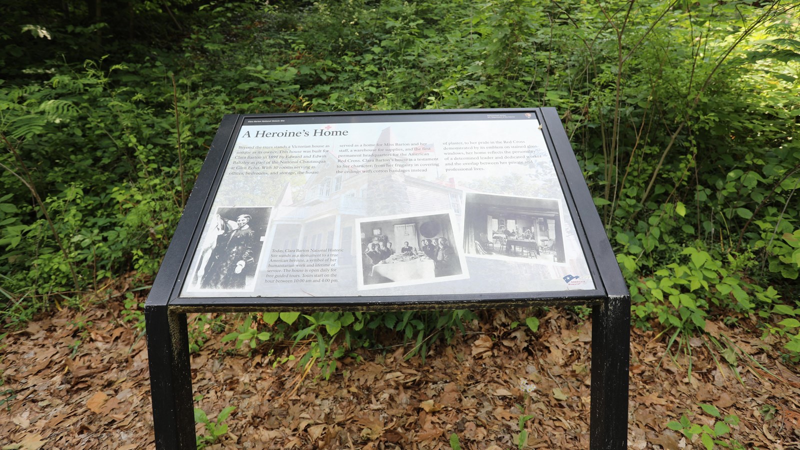 An angled information panel with photographs of Clara Barton by a horse, and seated in the home.