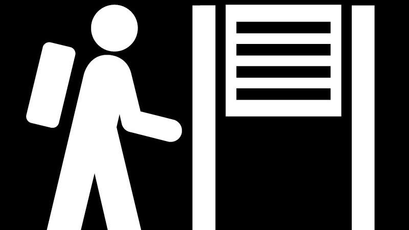 A black and white symbol of a hiker facing a sign.
