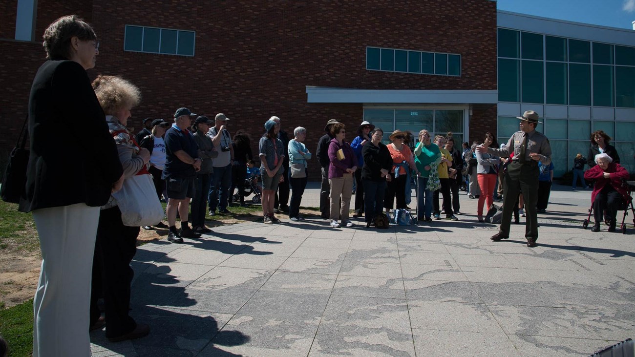 A ranger speaks to a crowd outside the Fort McHenry visitor center.