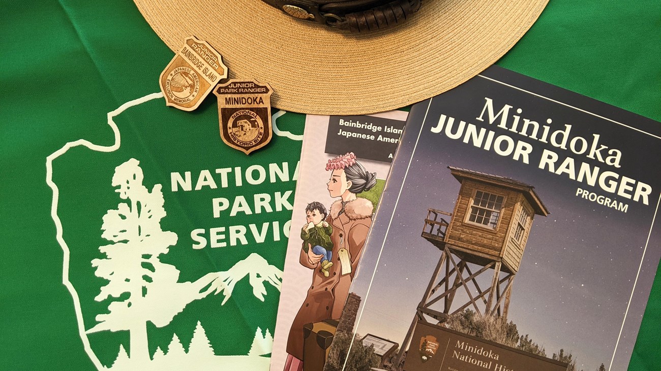 Junior Ranger booklets and badges on a table with a ranger hat and a National Park Service symbol.