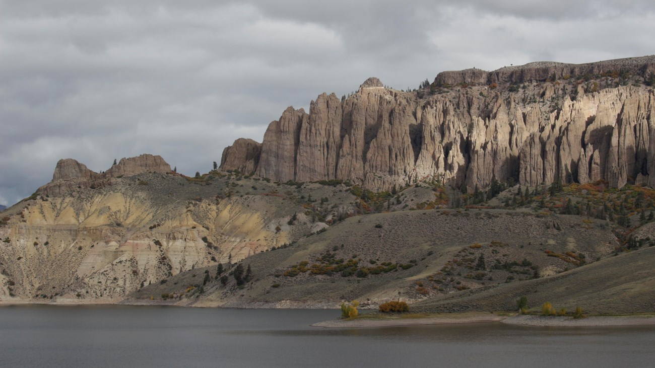 Geologic formations on the side of a mesa in front of a body of water