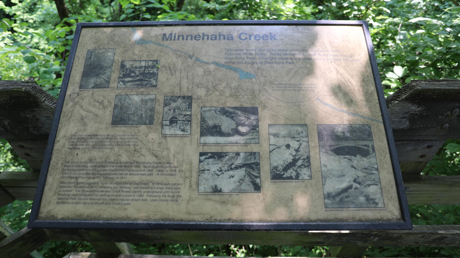 Information panel with a series of historic photos of the creek behind and far below this sign.