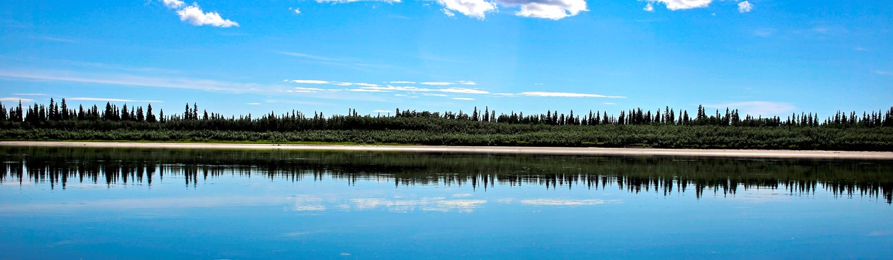 The Kobuk River reflecting the sky and clouds on a calm day.