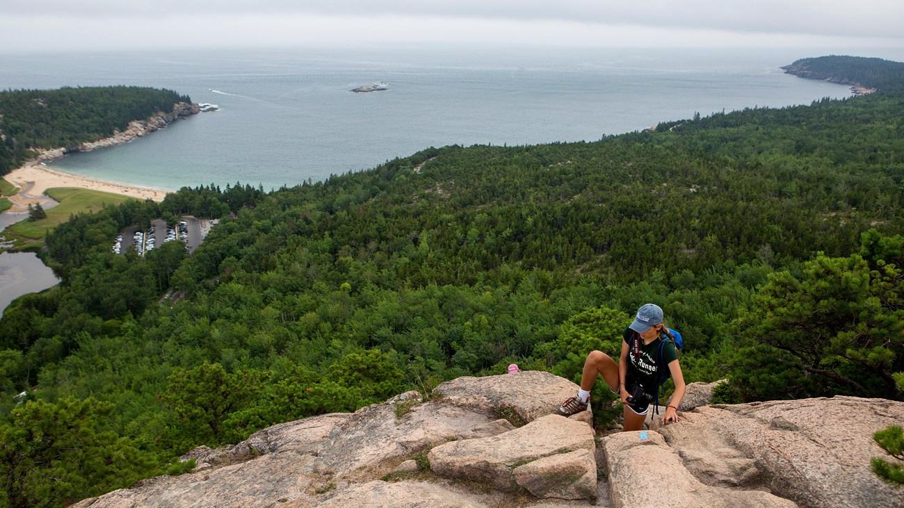 person climbing up rocks with a ocean view in the distance