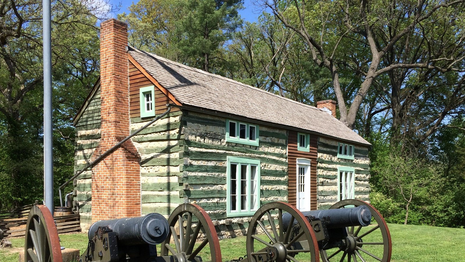 The Hardscrabble log cabin with Howitzer cannons in the foreground.
