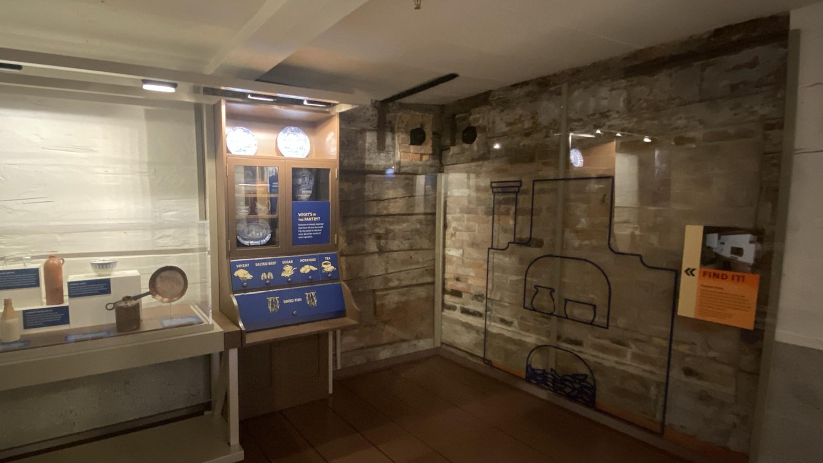 Kitchen exhibits, plexiglass on a corner of the wall exposed wood and brick outline of old oven