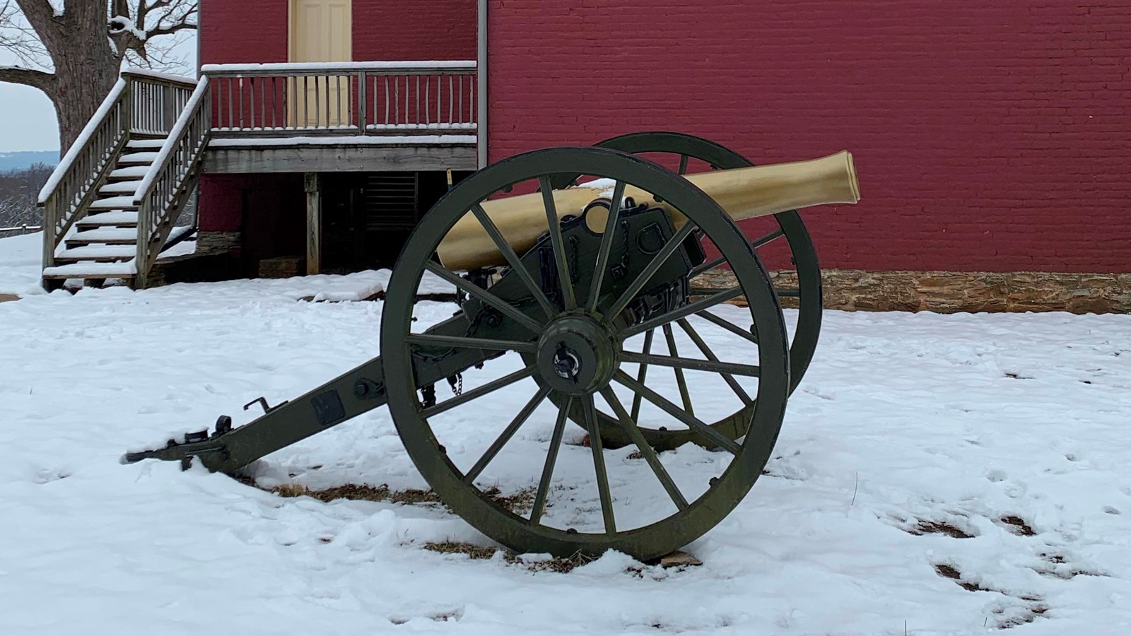 A reproduction Civil War next to a red brick two-story house.