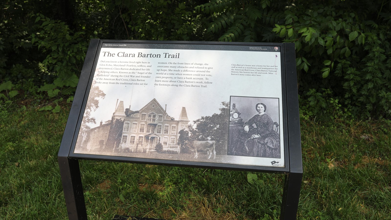 An angled information panel with an image of Clara Barton\'s Victorian house with a cow in the front.