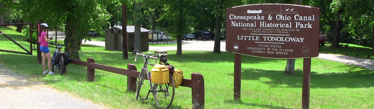 bicyclists stopped along a natural surface path near a modern and an historic historic