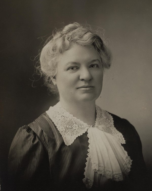 Portrait of a woman with her hair in an updo and wearing a blouse with a lace bow