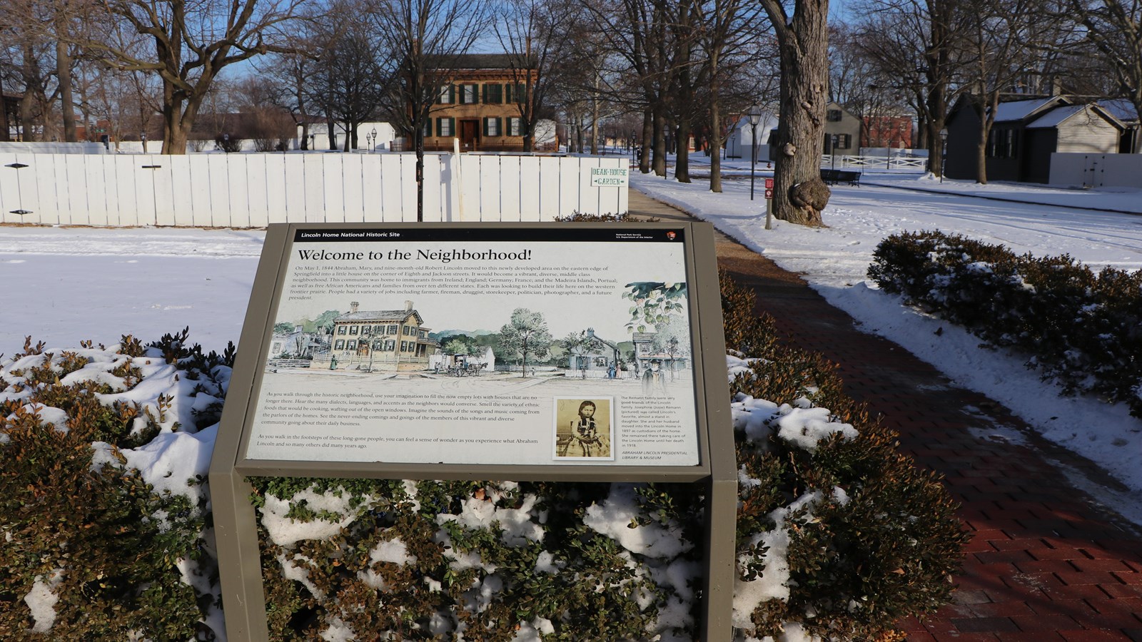 Outdoor wayside exhibit next to path that leads to the Lincoln Home in the Distance.