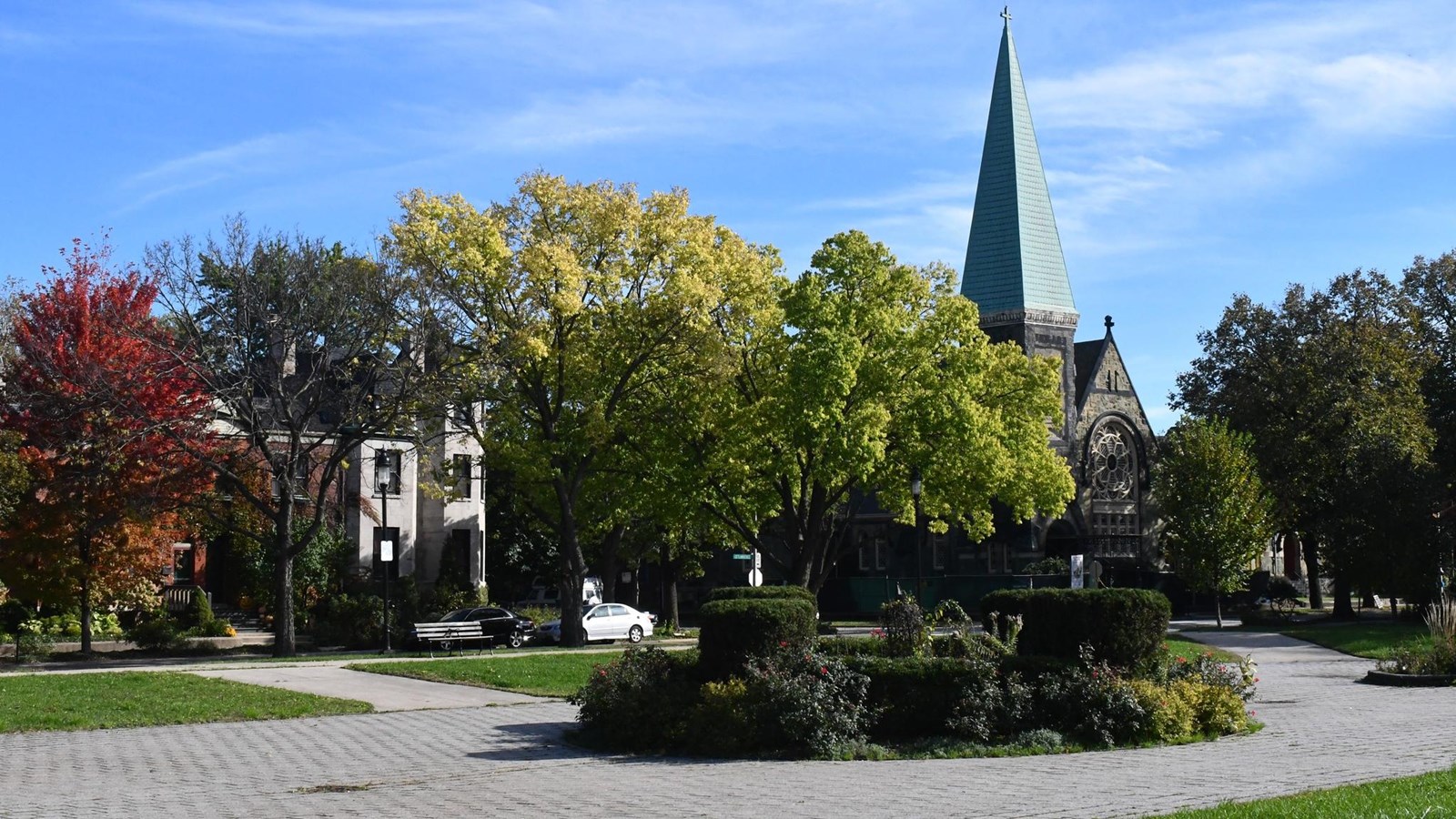 A photo of Arcade Park with flowers in bloom and the Greenstone Church in the background.