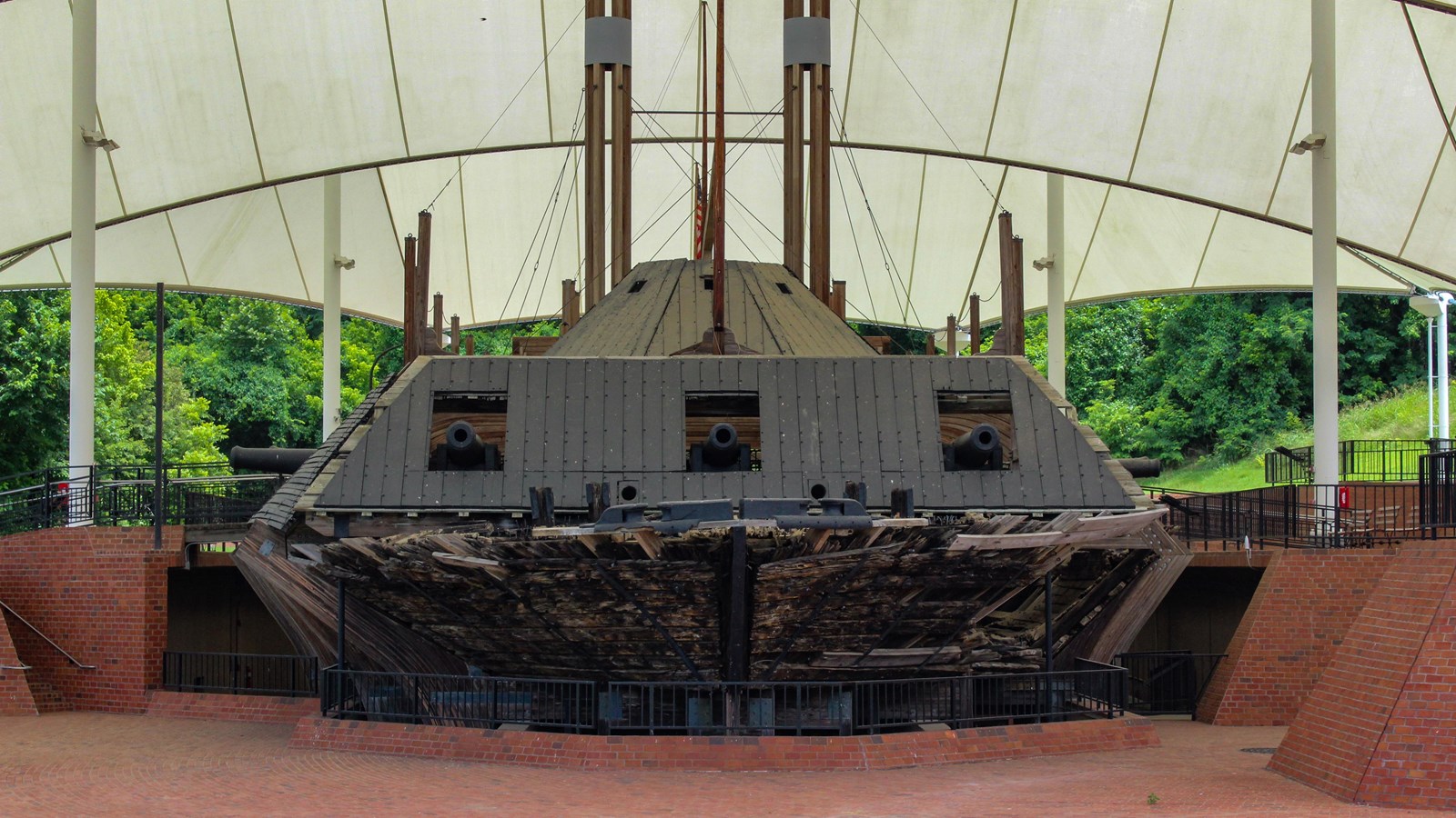 A large wooden and black ship sits on a brick floor with white canopy covering it