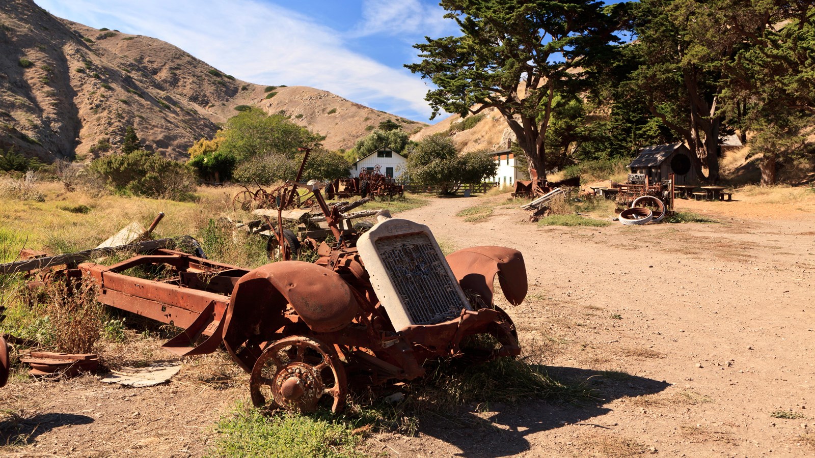 Historic farm implement in foreground with ranch houses in background.
