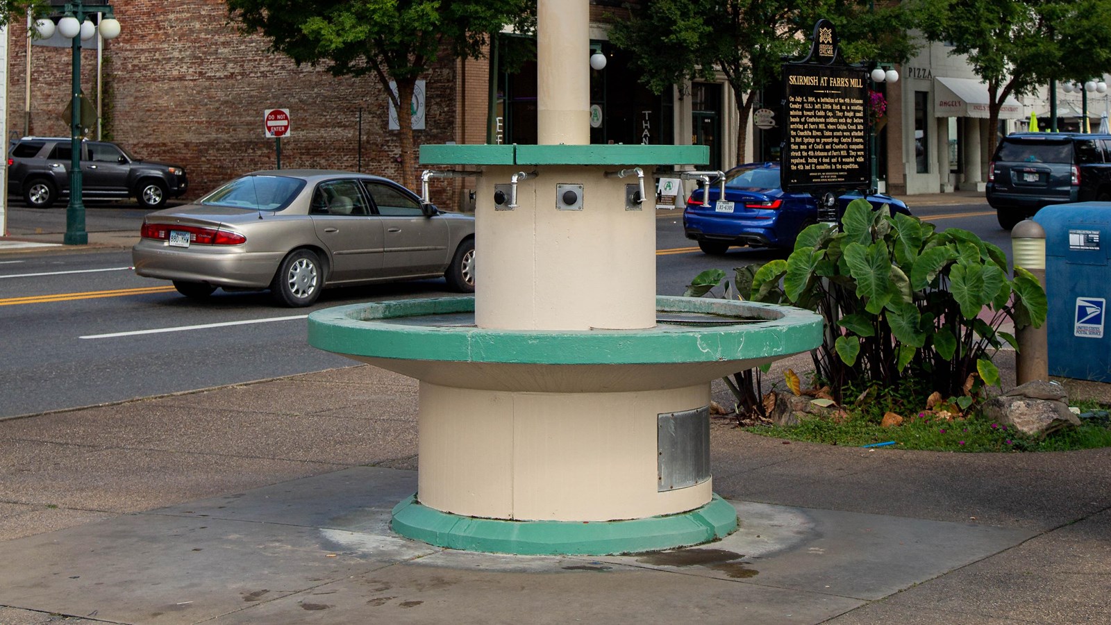 A water fountain with four spouts and a large umbrella roof covering the top