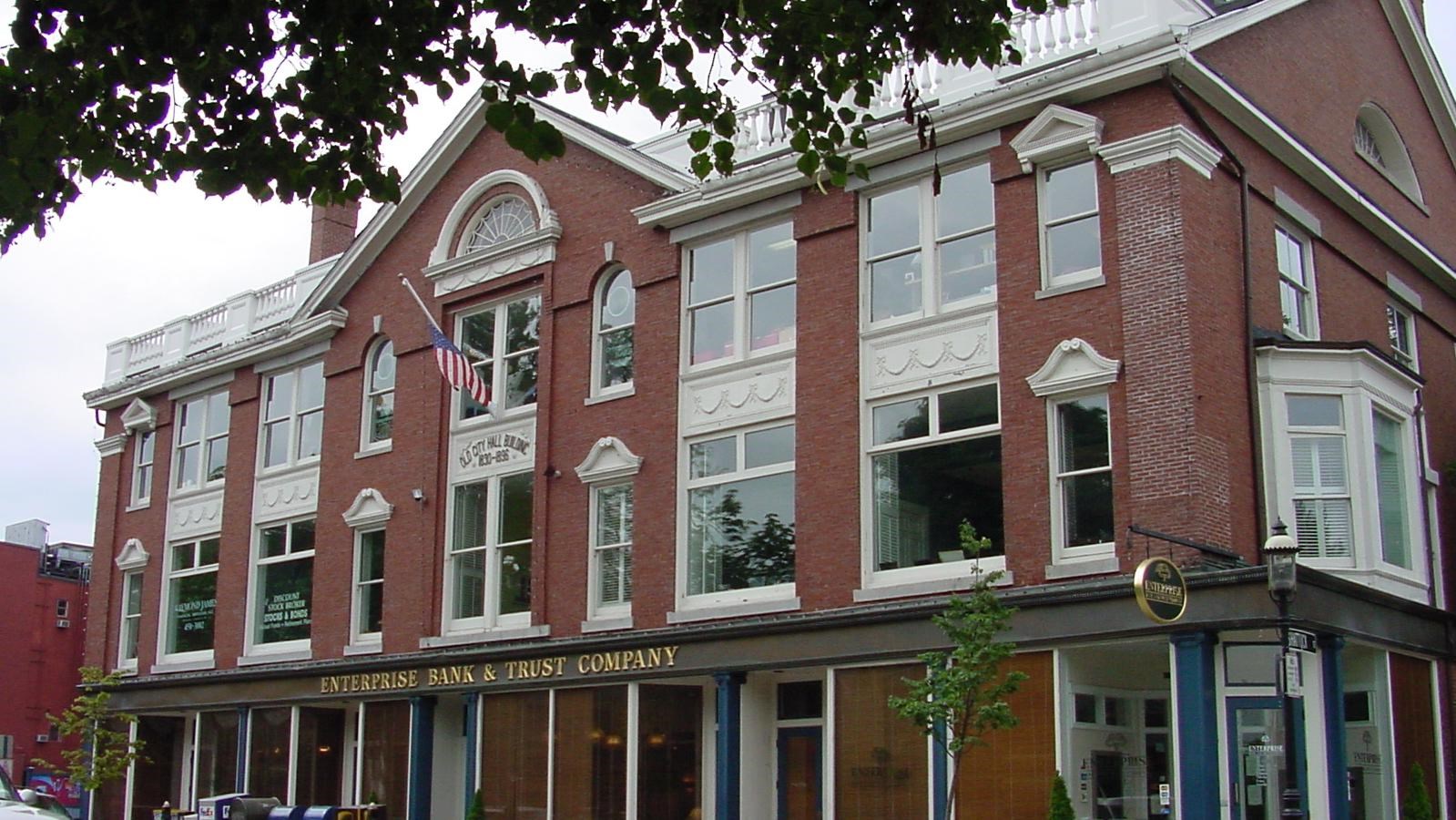 Brick building with tall windows, along a busy street. Words
