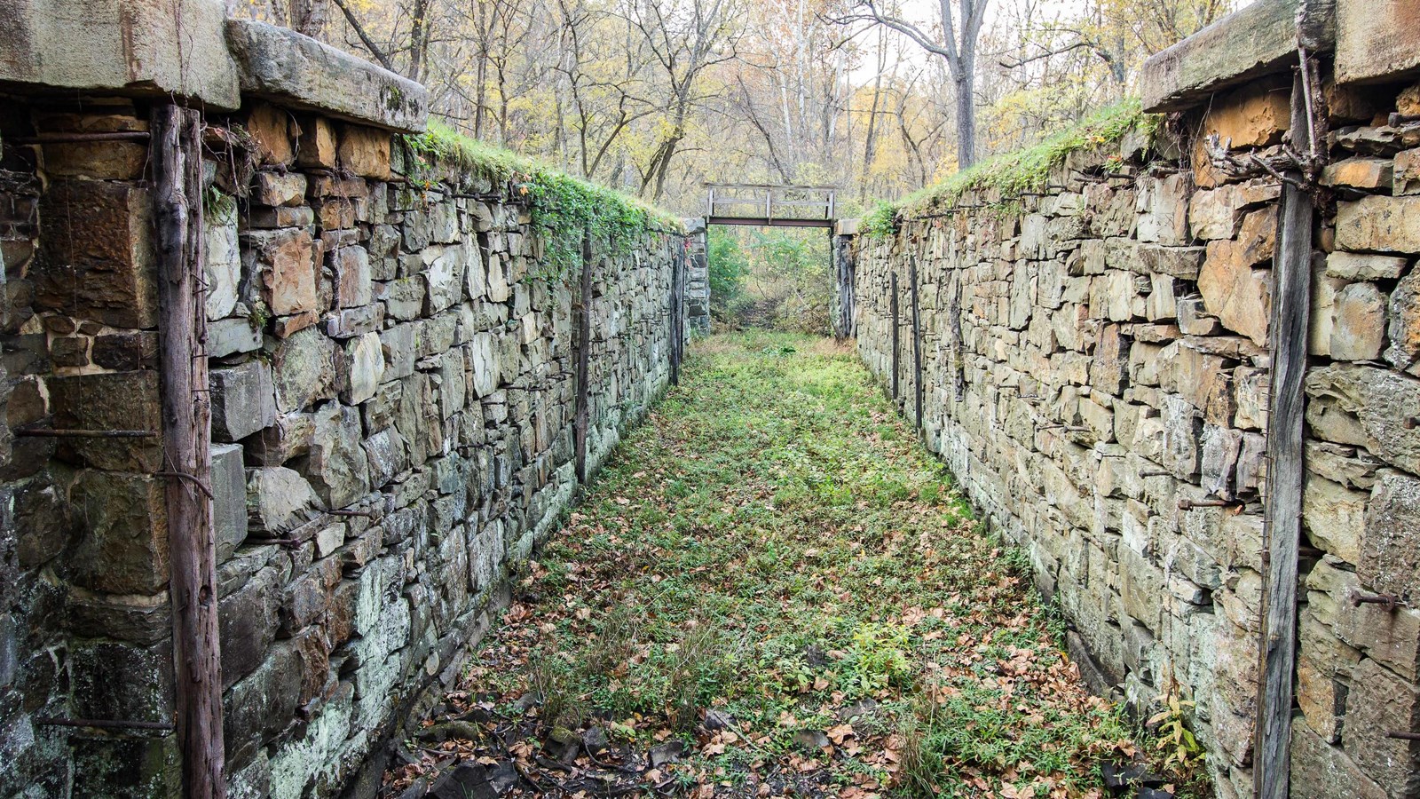A look through a lock, with long stone walls stretching up on the right and left.