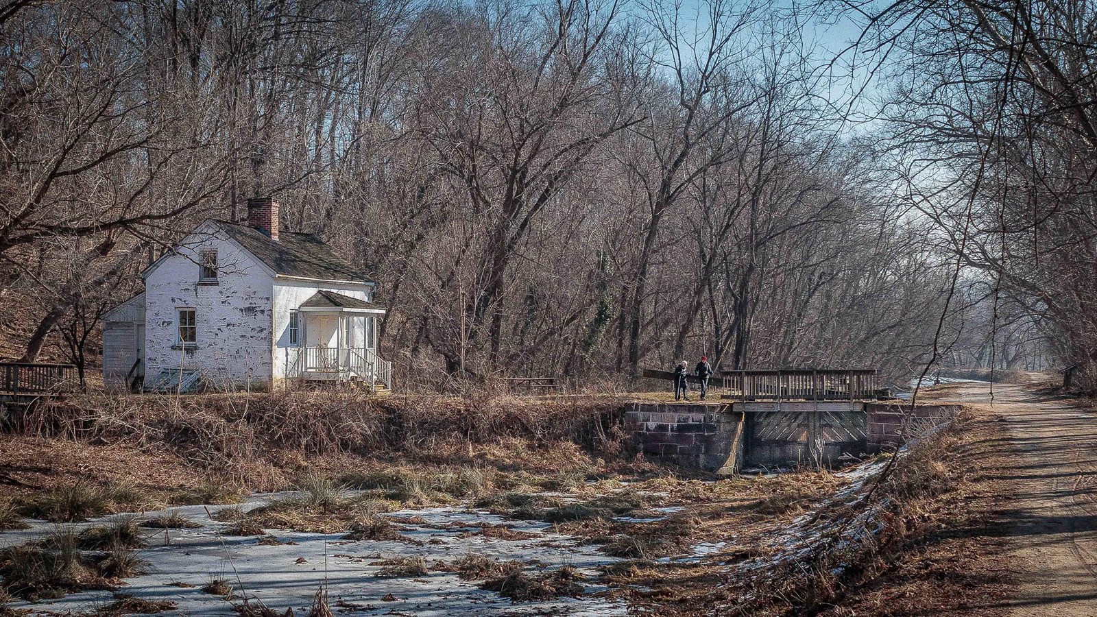 The water filled canal runs through a lock. A white lockhouse sits to the left. 