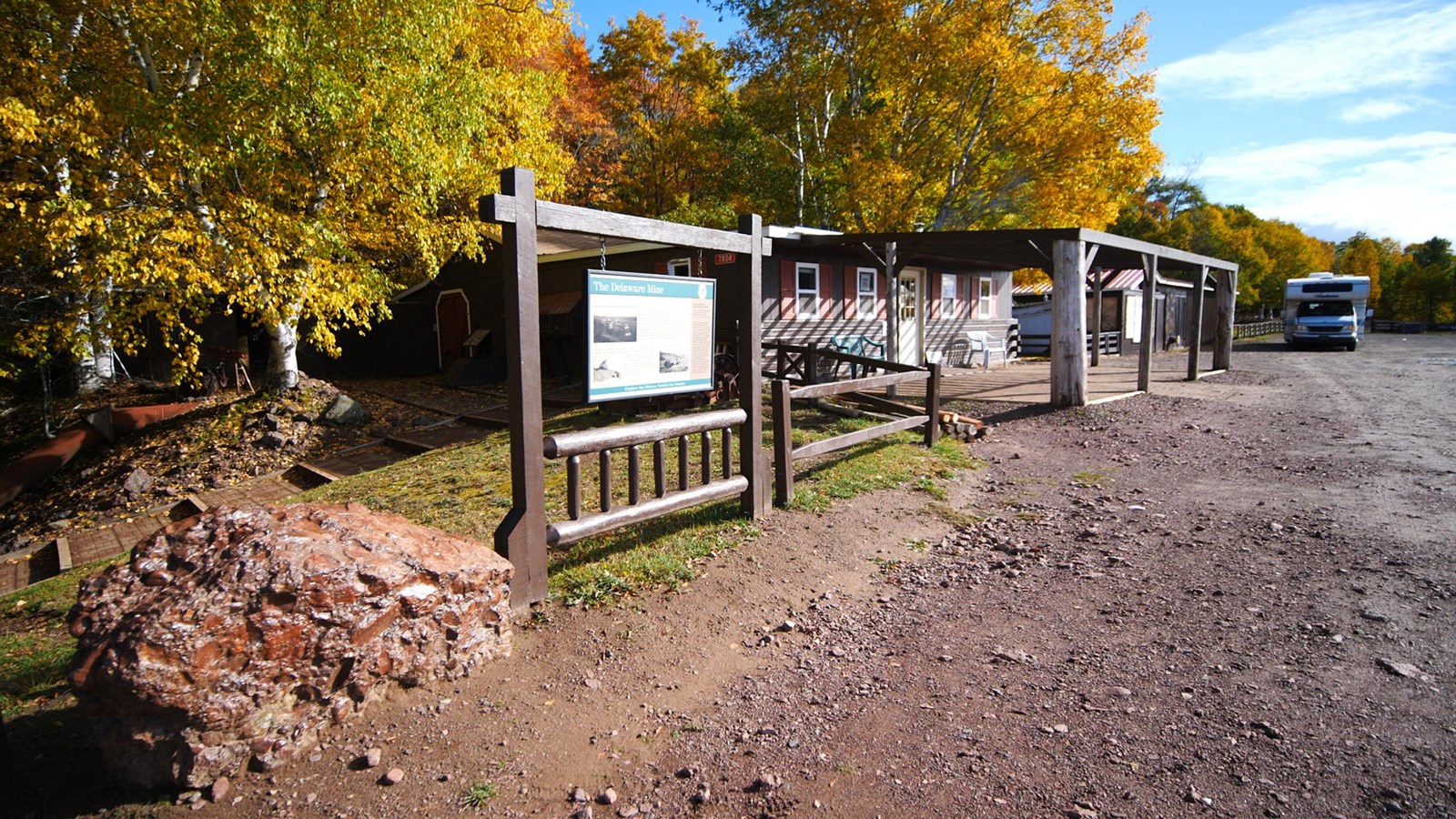 Fall scene of a single-story wooden building with autumnal trees in the background. 