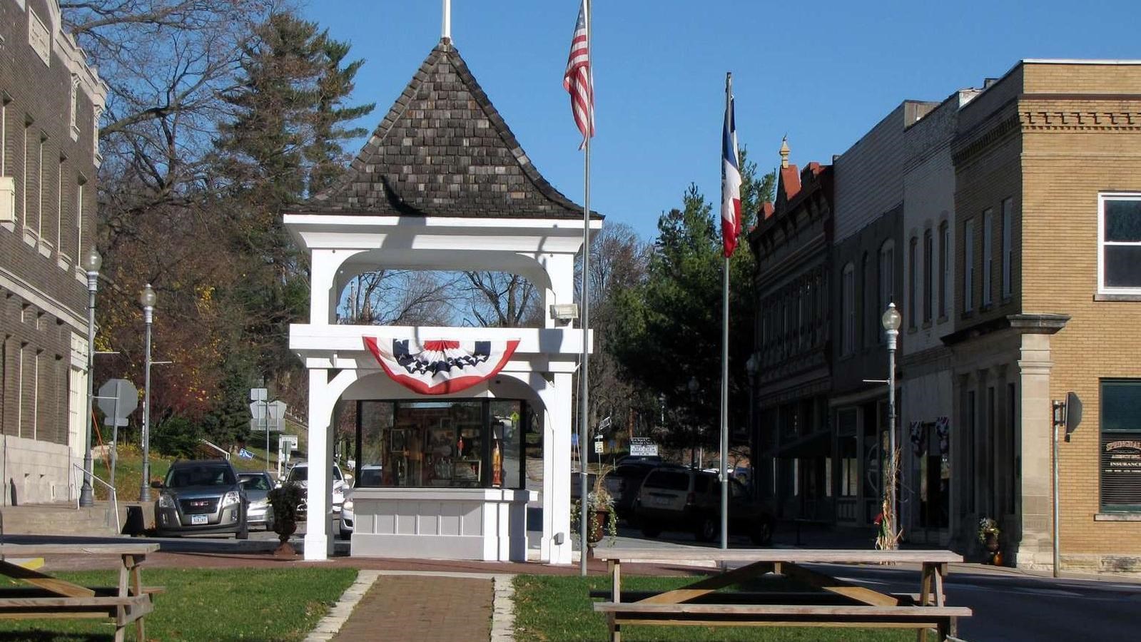 A white gazebo on a historic downtown street showcases local history with a art display.