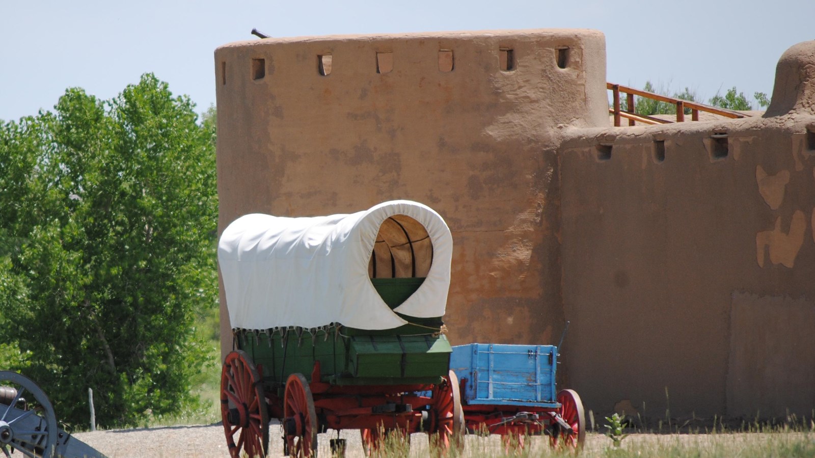 A round adobe tower stands over wagons and a cannon.