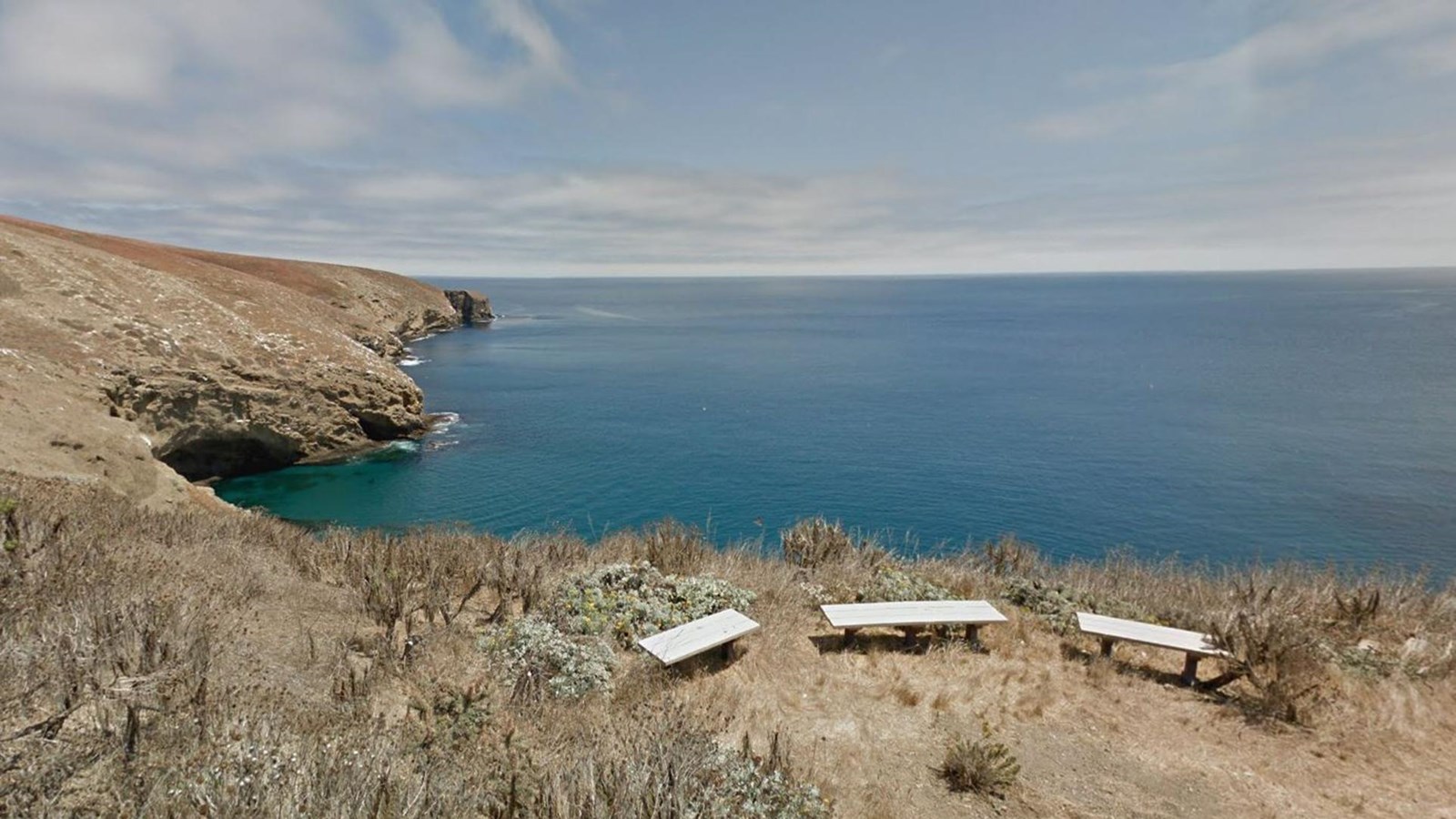 three benches on ocean bluff overlooking ocean. 