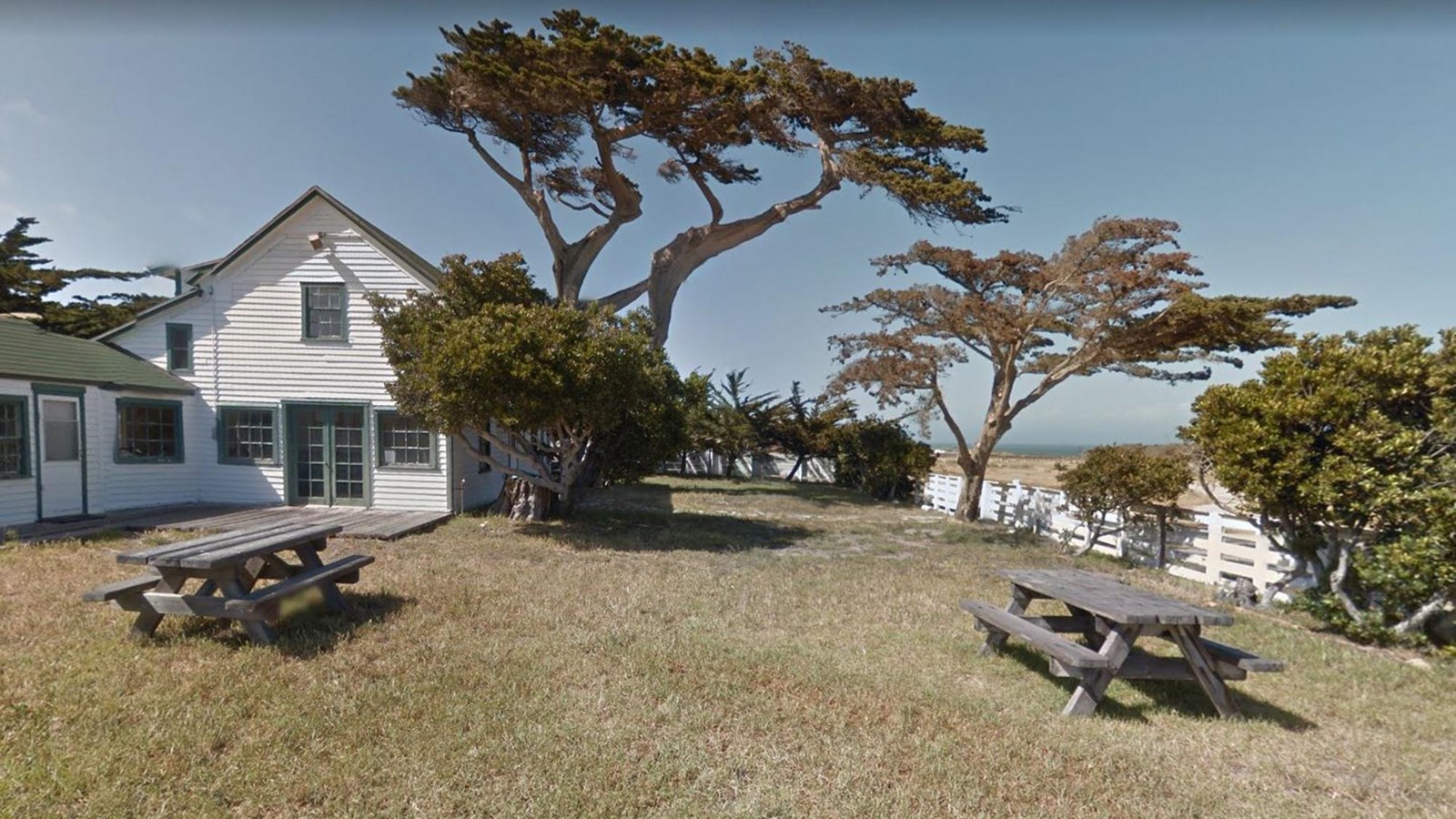 picnic area with tables next to ranch house and tall trees