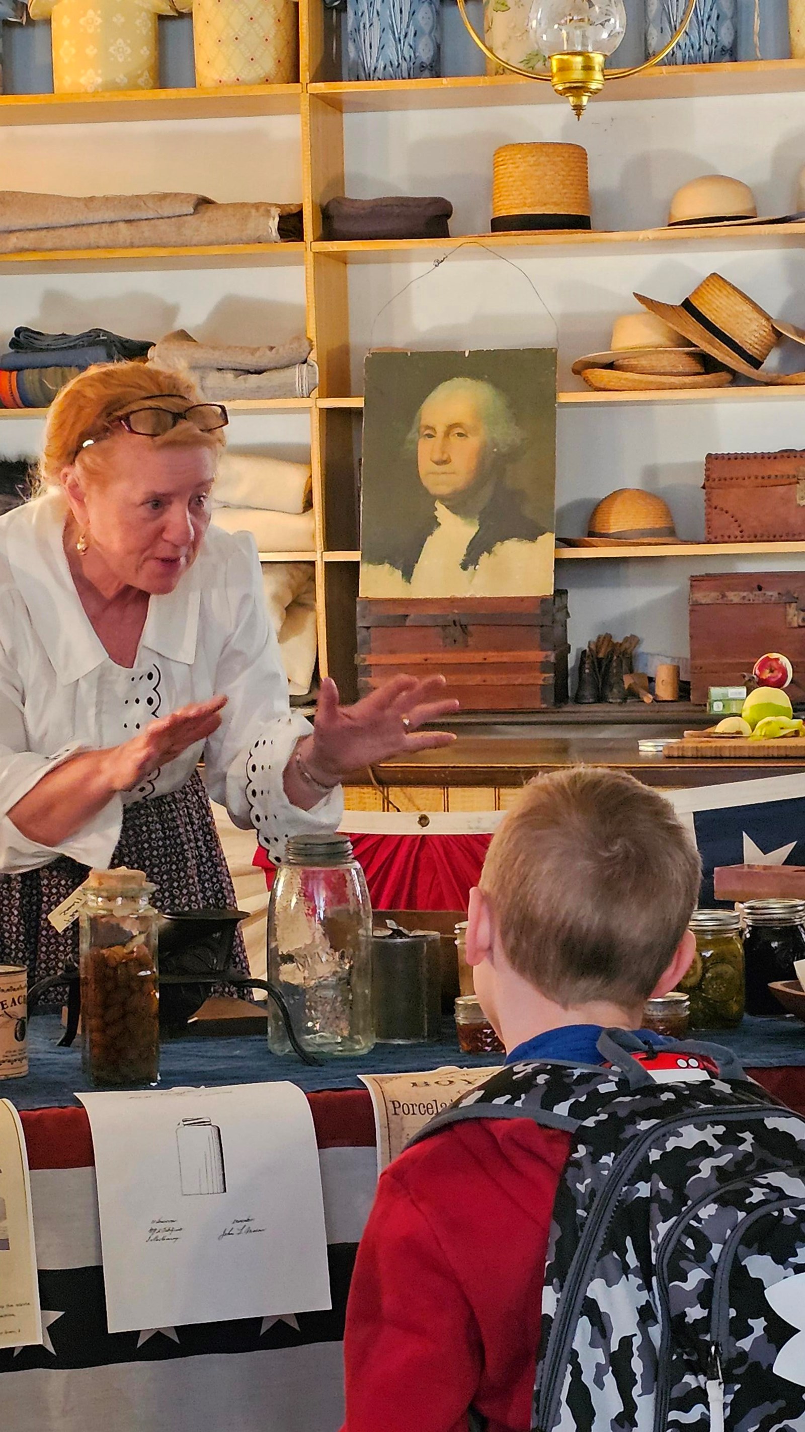 A woman in period clothing talking to children.