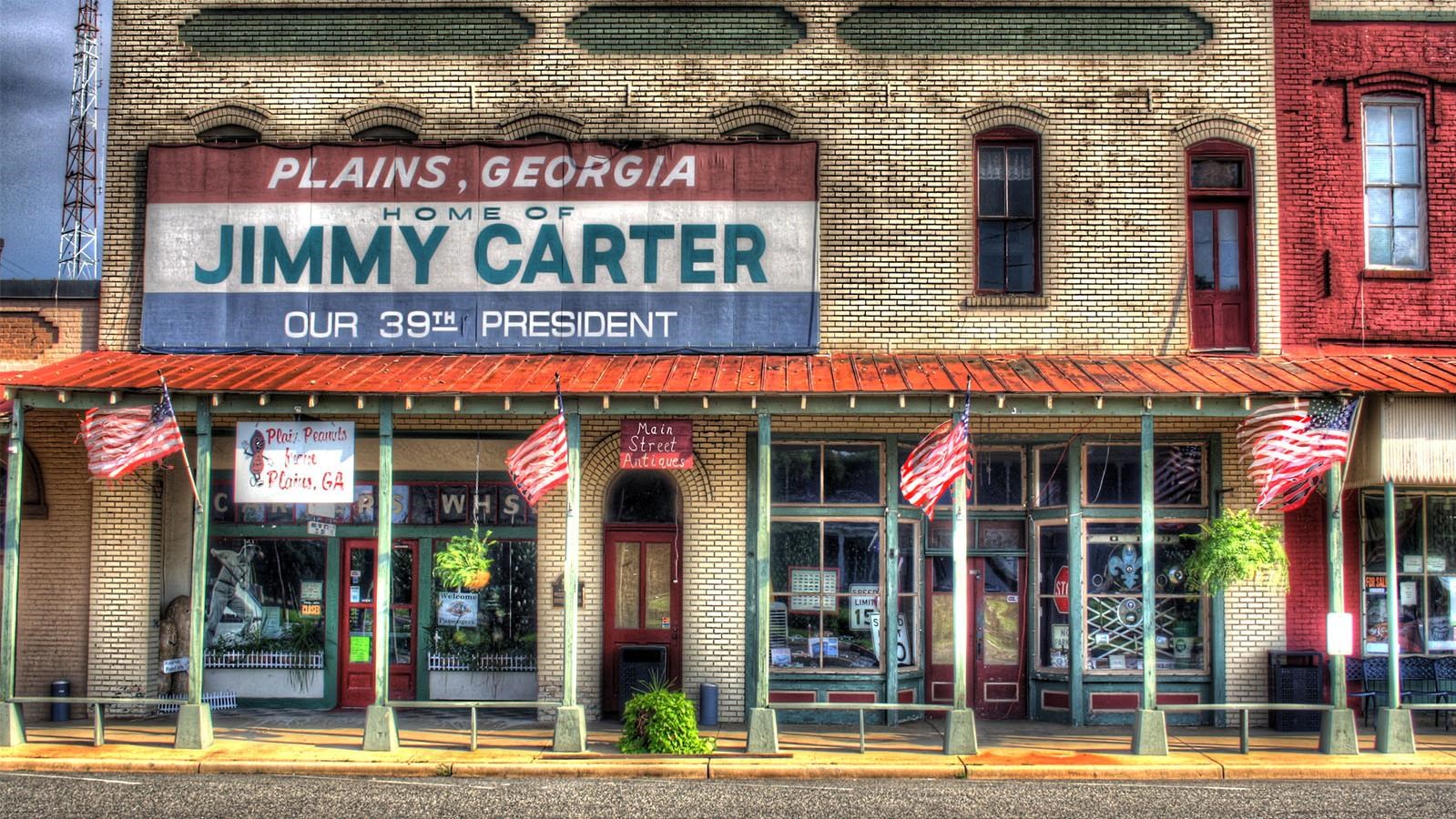 A beige brick building with a large red, white,and blue sign saying
