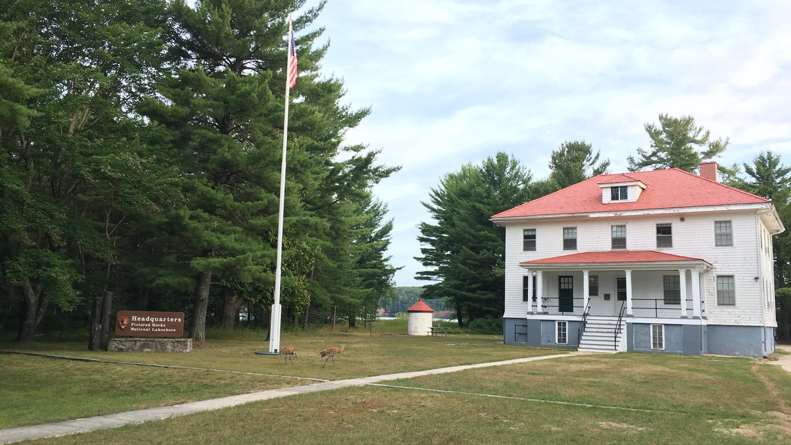 Munising U.S. Coast Guard Station at Sand Point on a summer day. Two sandhill cranes wander the lawn