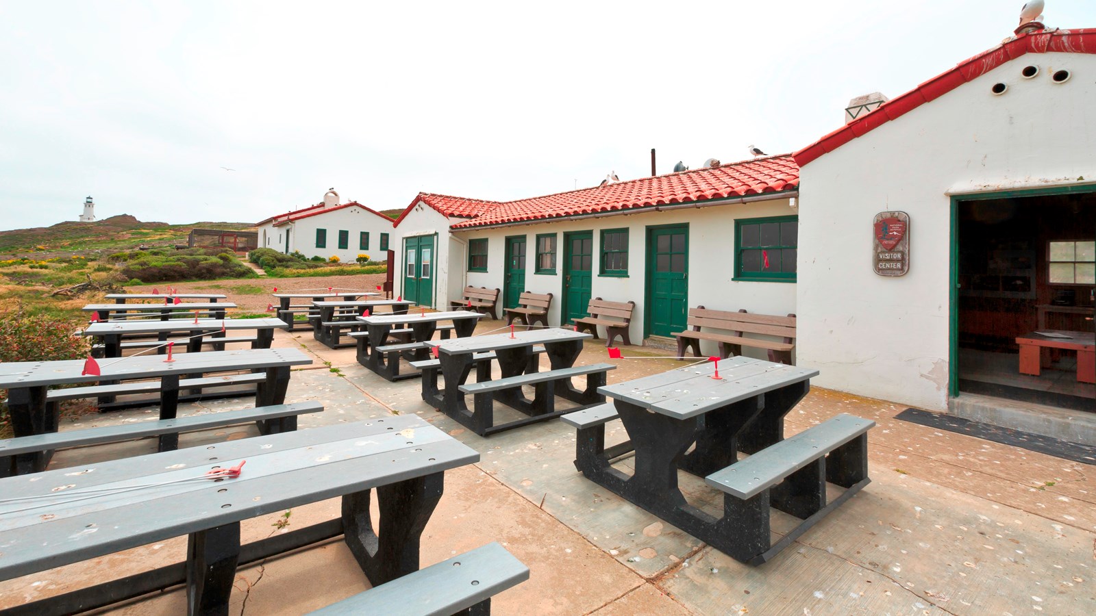 picnic tables outside stucco building with red tile roof