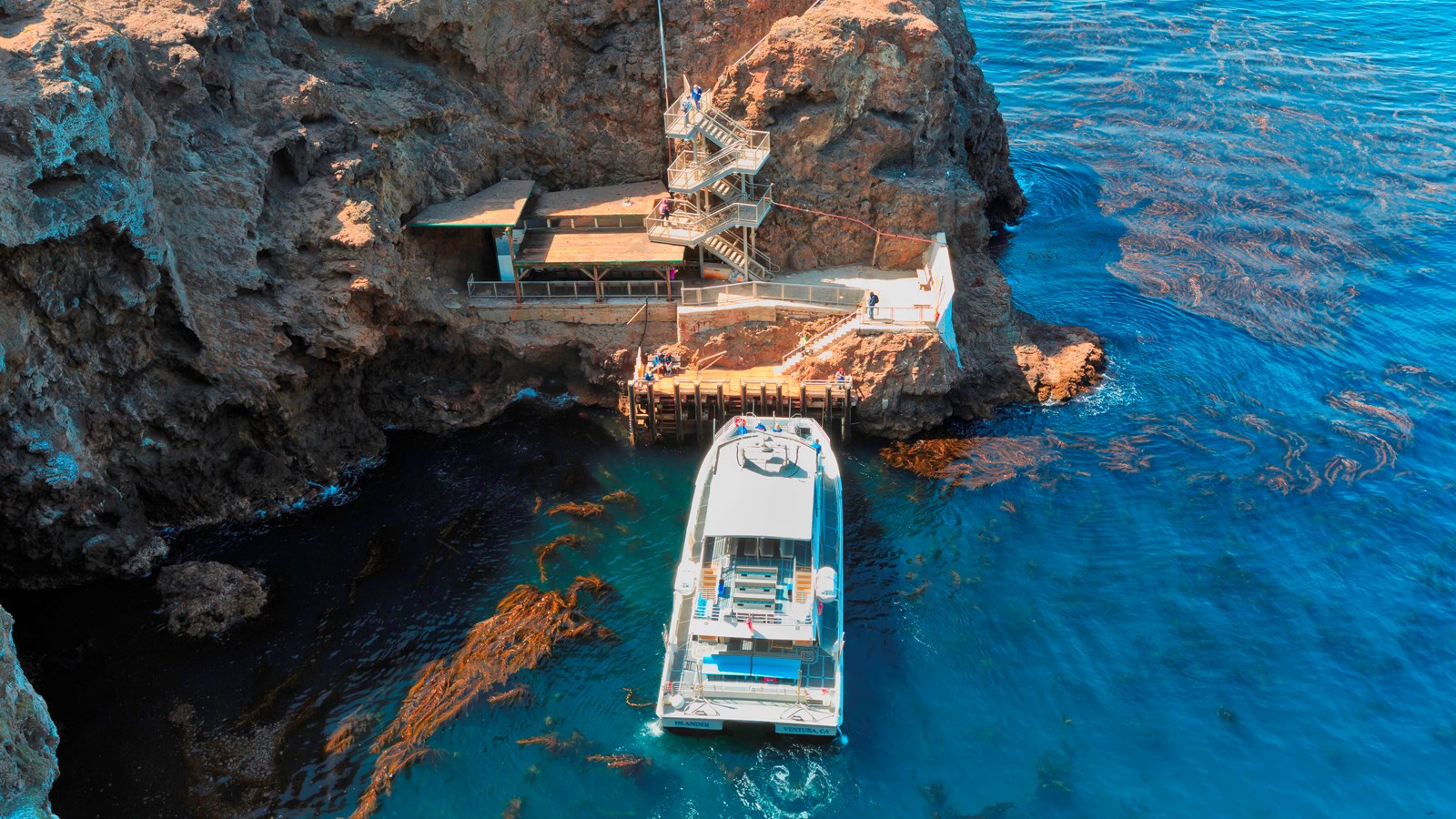 boat pulling into dock next to steep cliffs