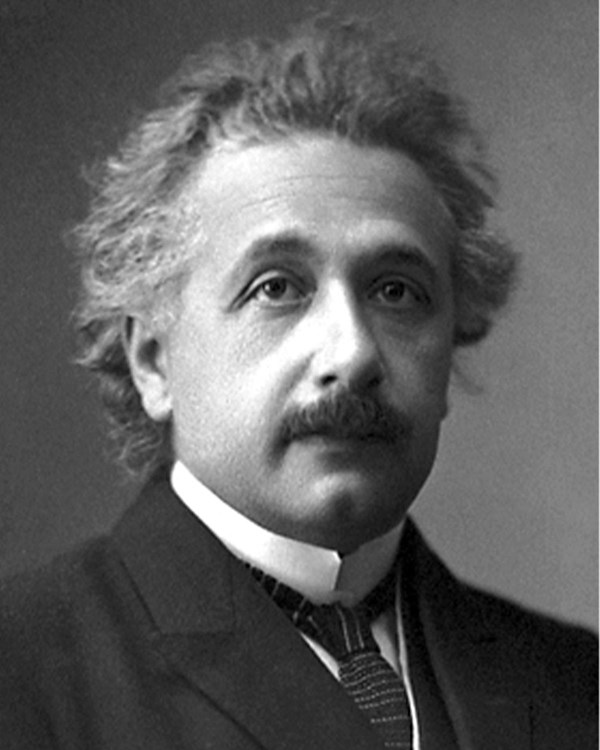 Black and white photograph of a man in a black suit with white collar, moustache, and frizzy hair.