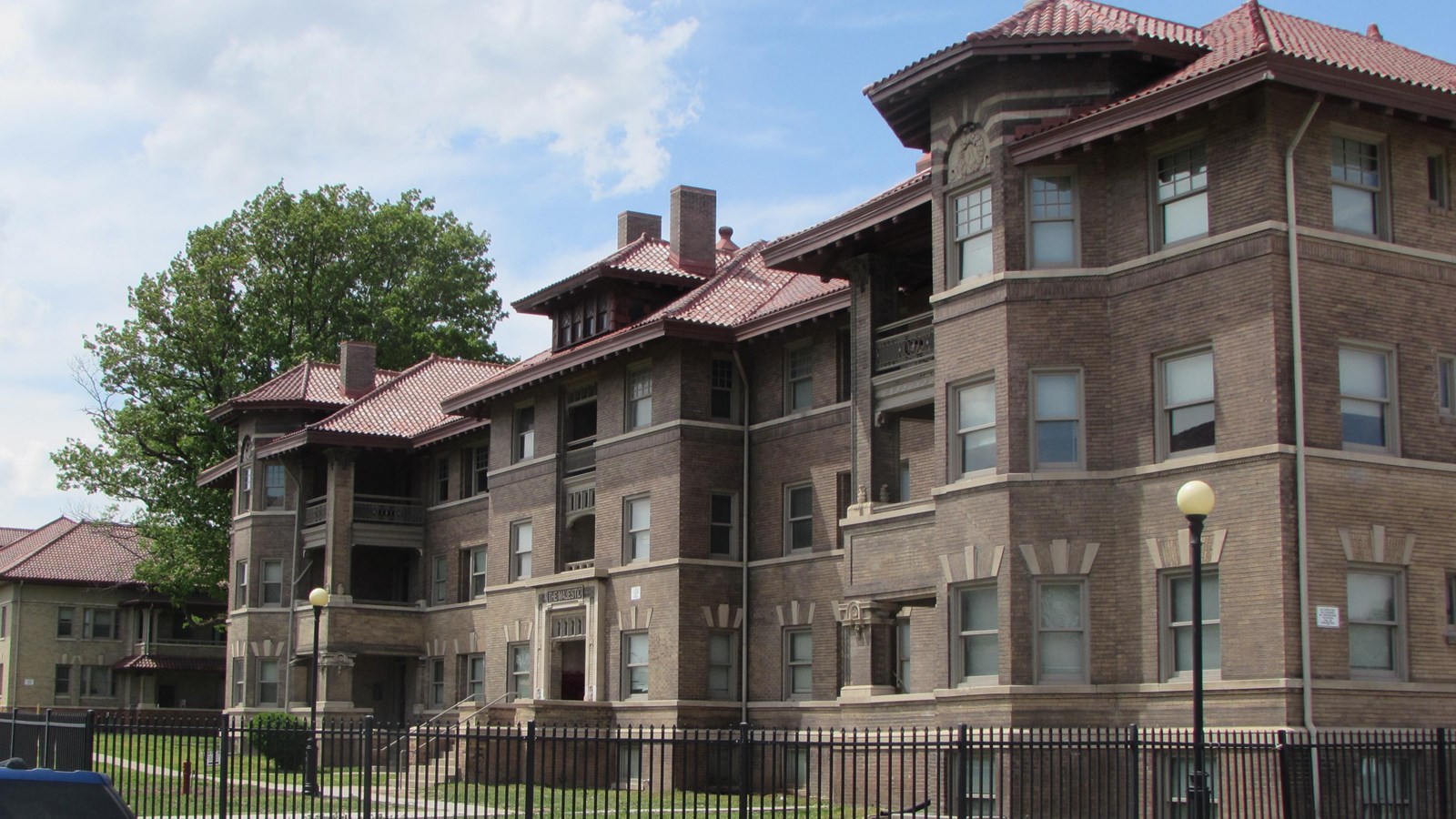Two three story brick apartment buildings, red tile roofs. Bay windows and set backs. Courtyard