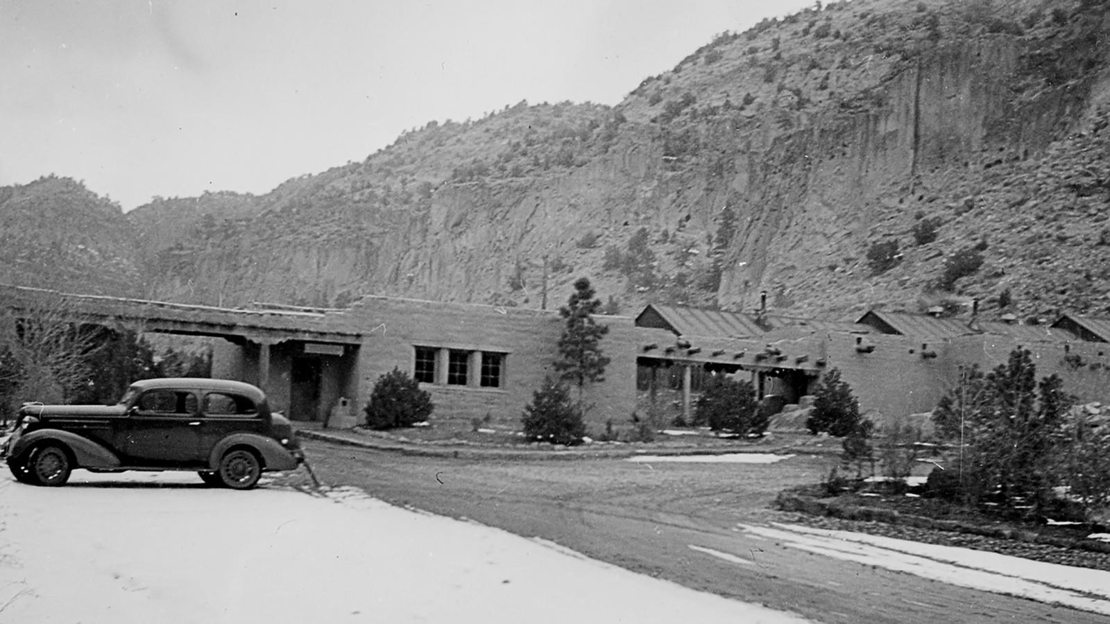 a stone building, an old car, and snow